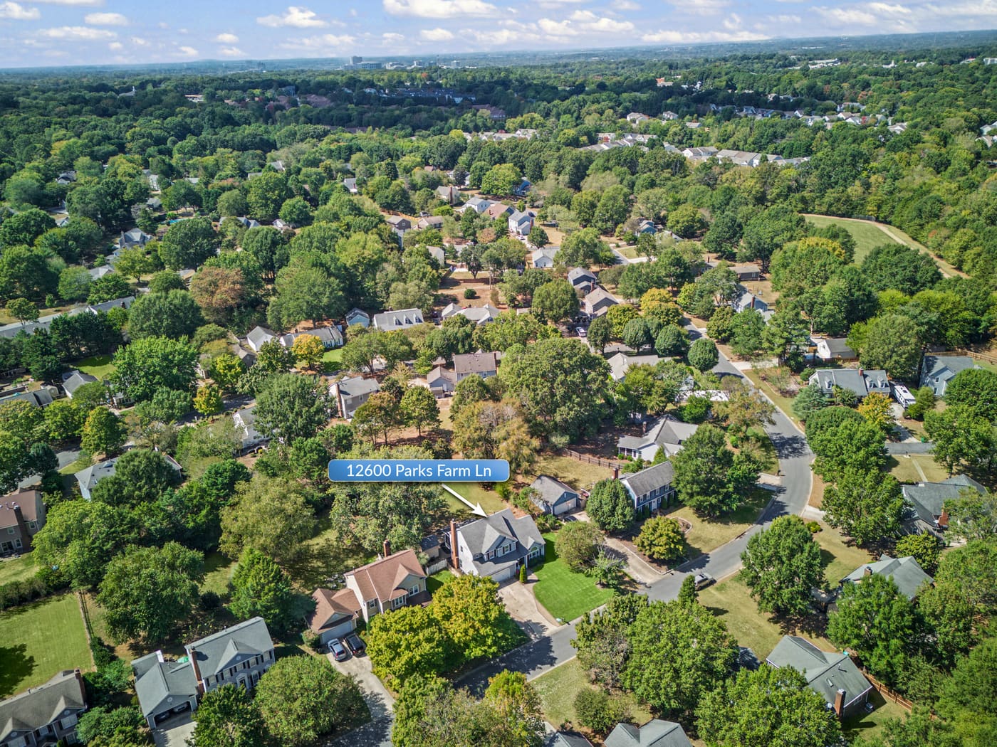 A higher aerial view of the neighborhood and tree canopy, with the home marked by a label.