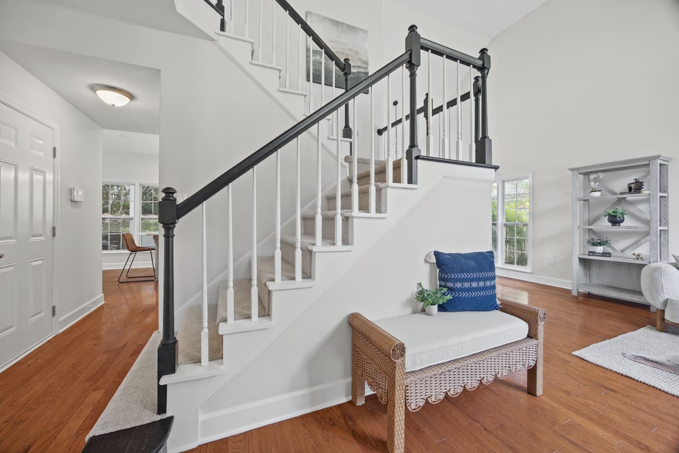 The staircase off the foyer, with a black handrail, white balusters and carpeted treads.